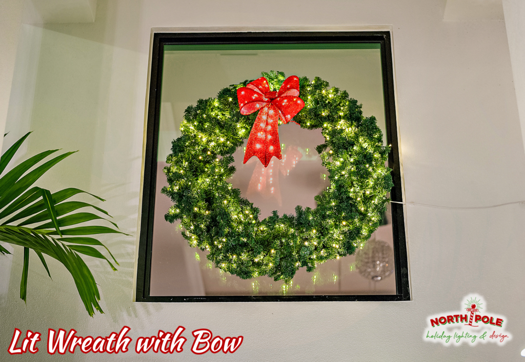 Traditional holiday wreath with a large red velvet bow and warm white lights mounted on a luxury Jupiter home.