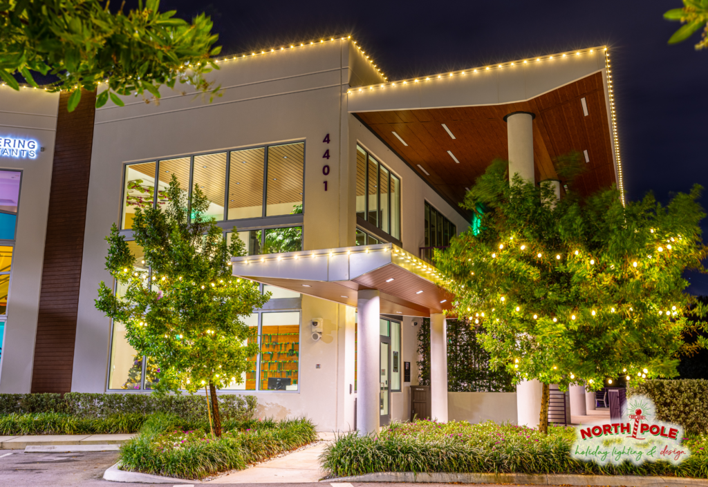 Commercial holiday roofline lighting on a modern office plaza in West Palm Beach with tree wraps.