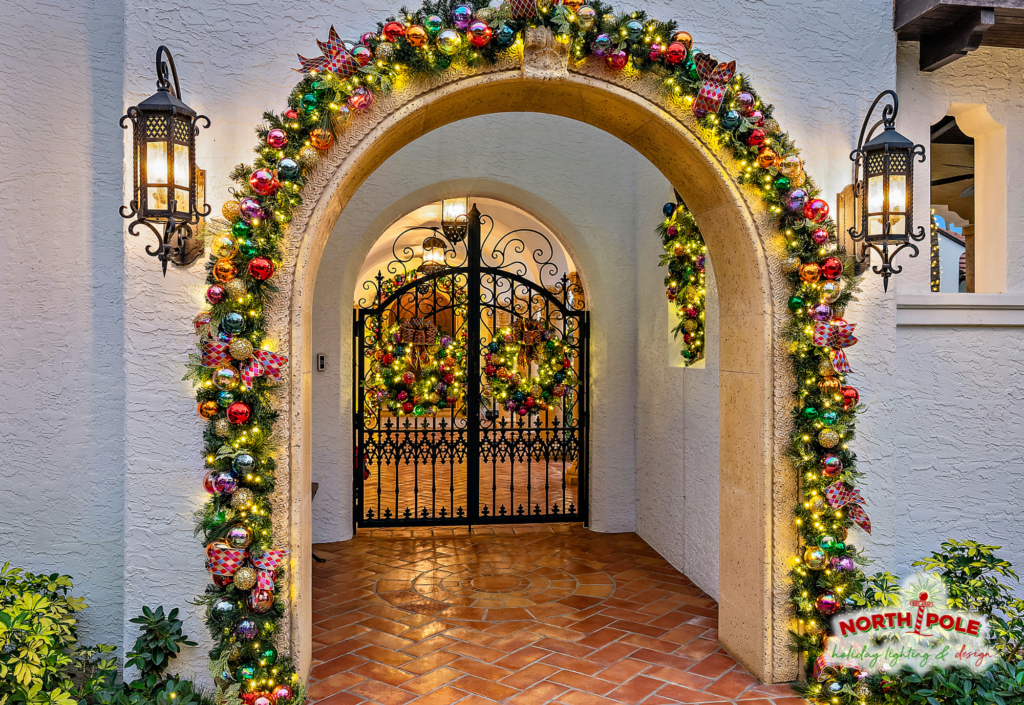 Custom holiday garland and ornament display on a Mediterranean archway in PGA National, Palm Beach Gardens.