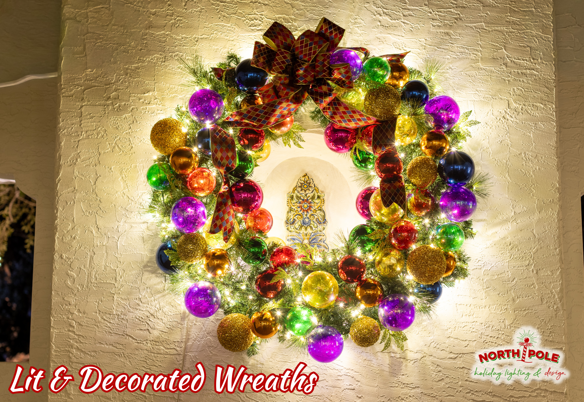 Large custom-decorated holiday wreaths with multi-colored ornaments and warm white LEDs in Jupiter.