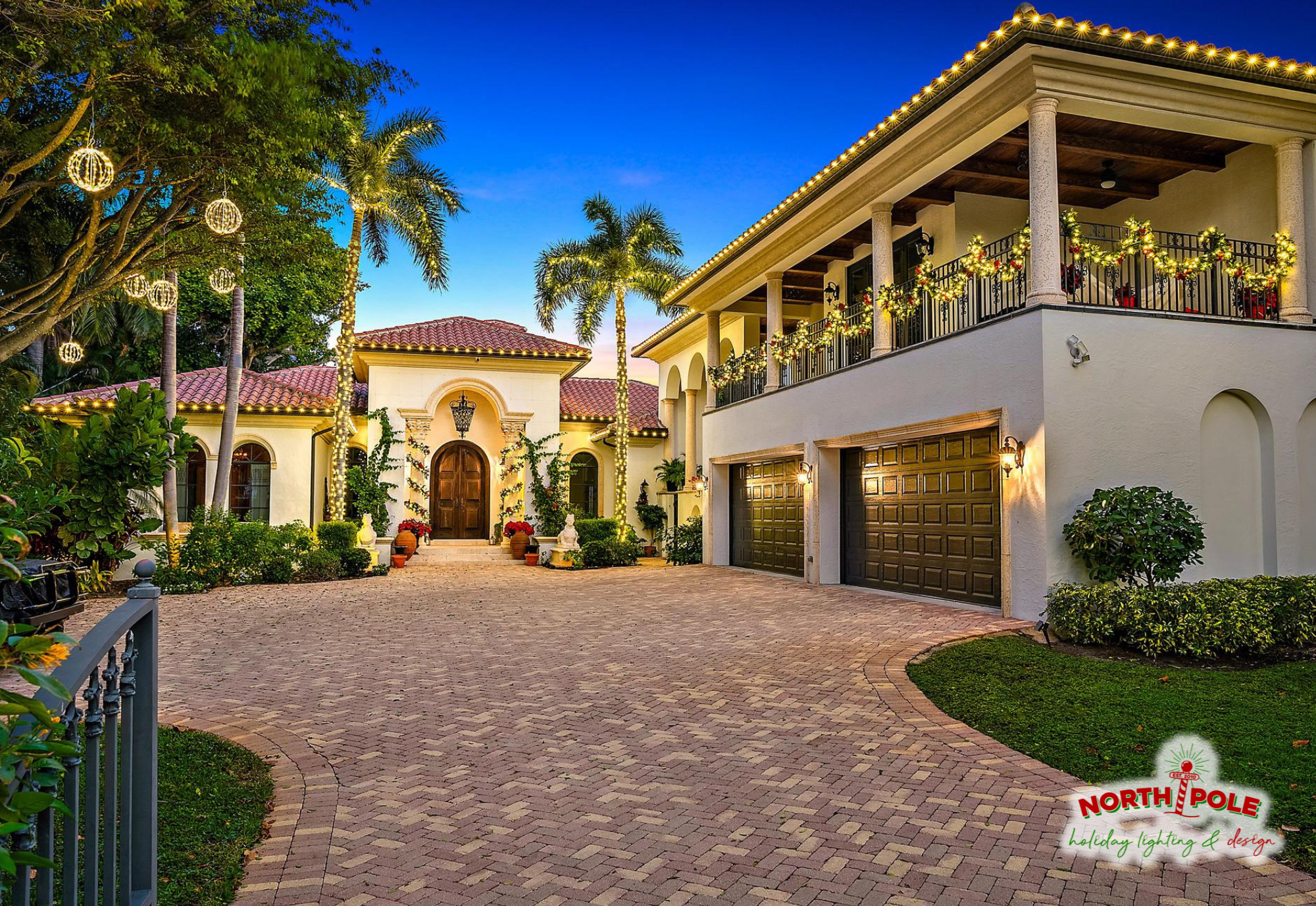 Luxury residential holiday lighting in West Palm Beach with warm white LED rooflines, lit balcony garland, and hanging light spheres on a Mediterranean estate.