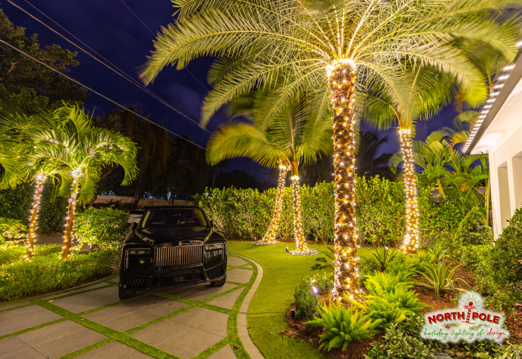 Luxury estate holiday lighting in Palm Beach featuring warm white LED palm tree wraps and a high-end driveway display.