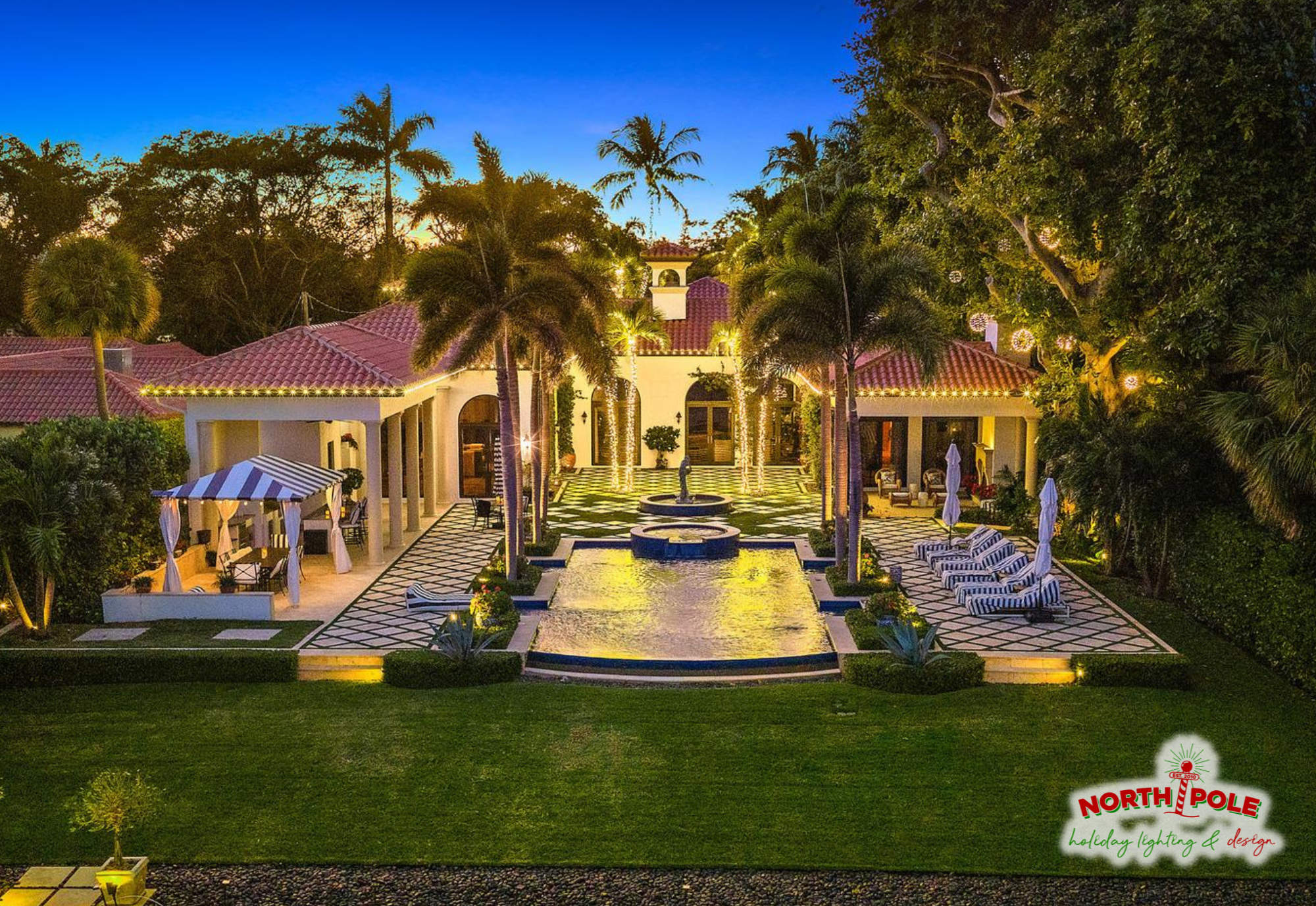 Luxury backyard holiday lighting in Royal Palm Beach with warm white LED rooflines, lit palm trees, and hanging globe lights over a poolside patio.
