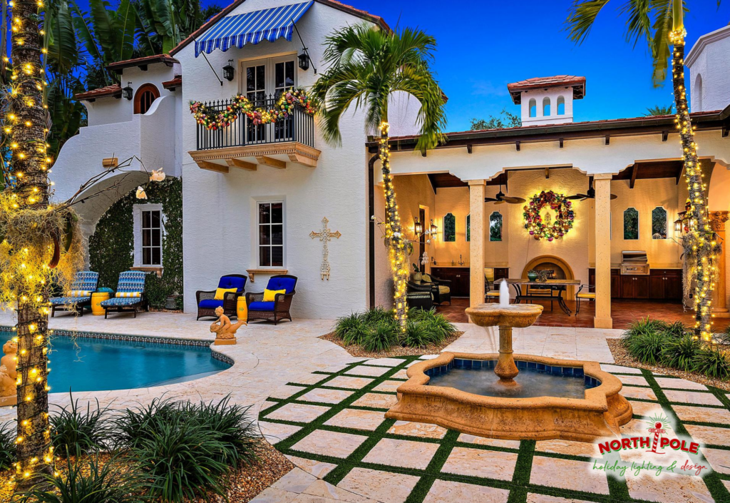 Luxury Delray Beach estate featuring custom-lit holiday wreaths and balcony garland with warm white LED palm tree wraps by a private pool.
