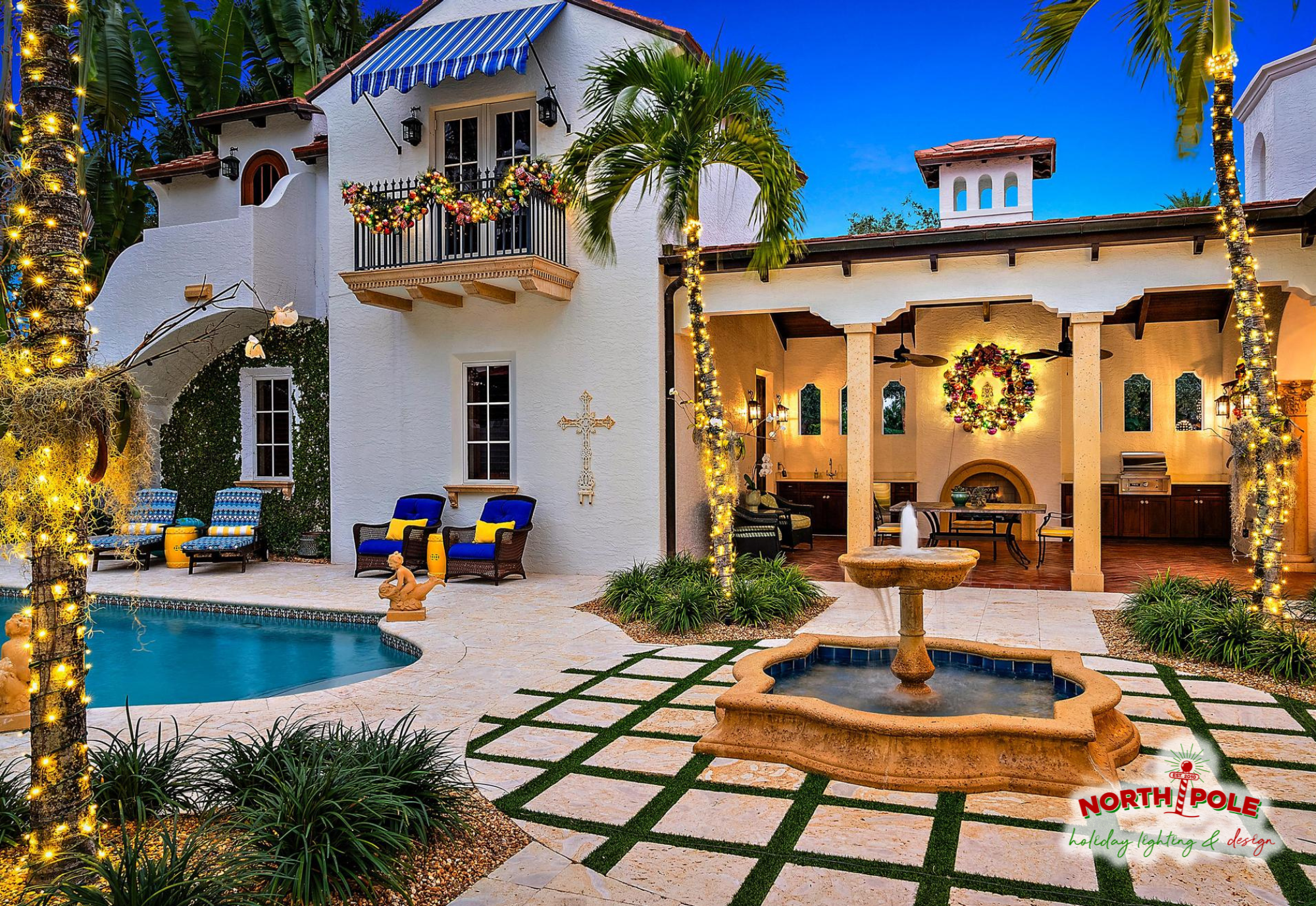 Luxury Delray Beach estate featuring custom-lit holiday wreaths and balcony garland with warm white LED palm tree wraps by a private pool.