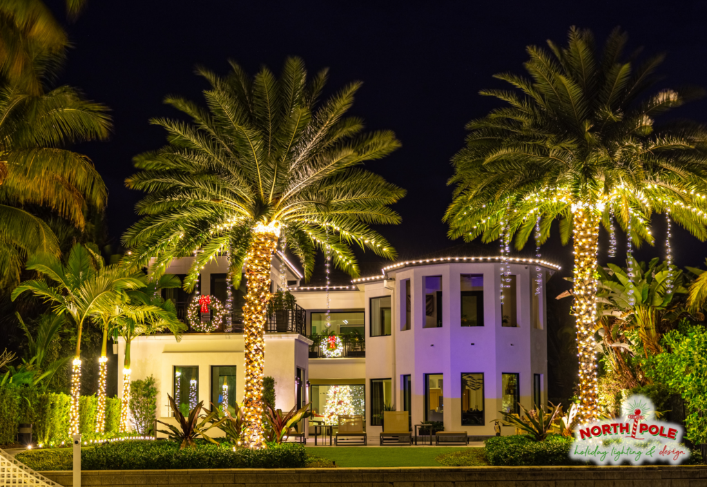 Waterfront estate holiday lighting on Singer Island featuring warm white LED rooflines and palm tree wraps reflected in a private pool.