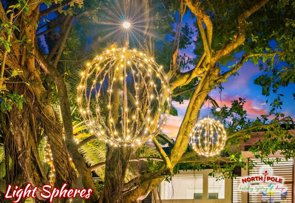 Hanging warm white LED light spheres of varying sizes suspended from a mature Banyan tree canopy in Stuart.