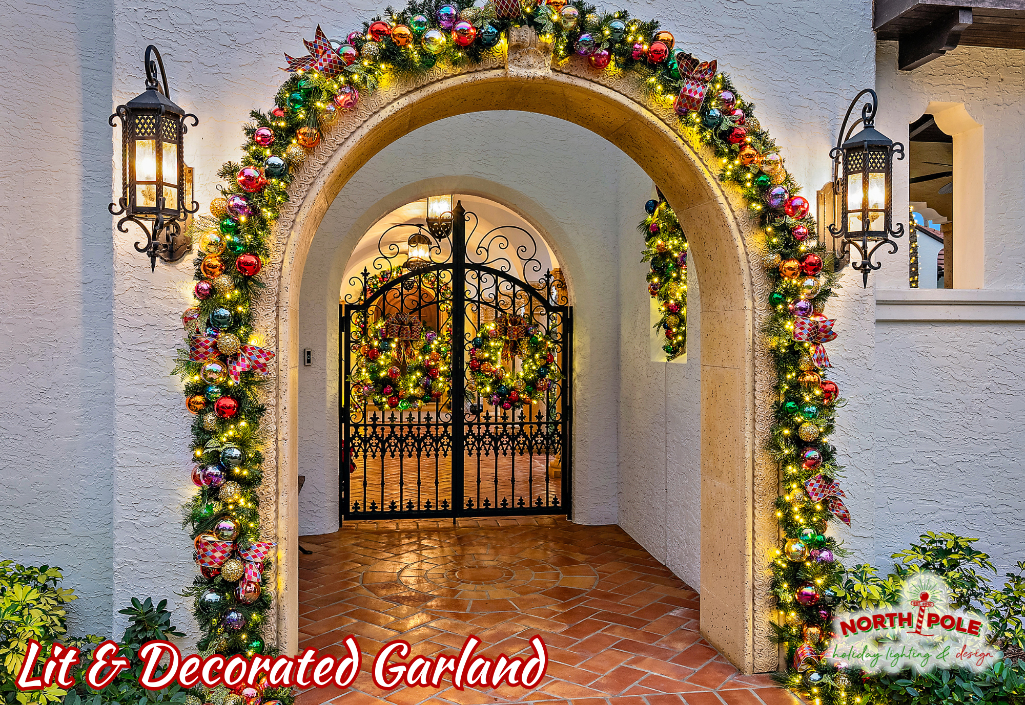 Luxury holiday garland and wreath installation on a grand stone archway at a Jupiter Island estate.
