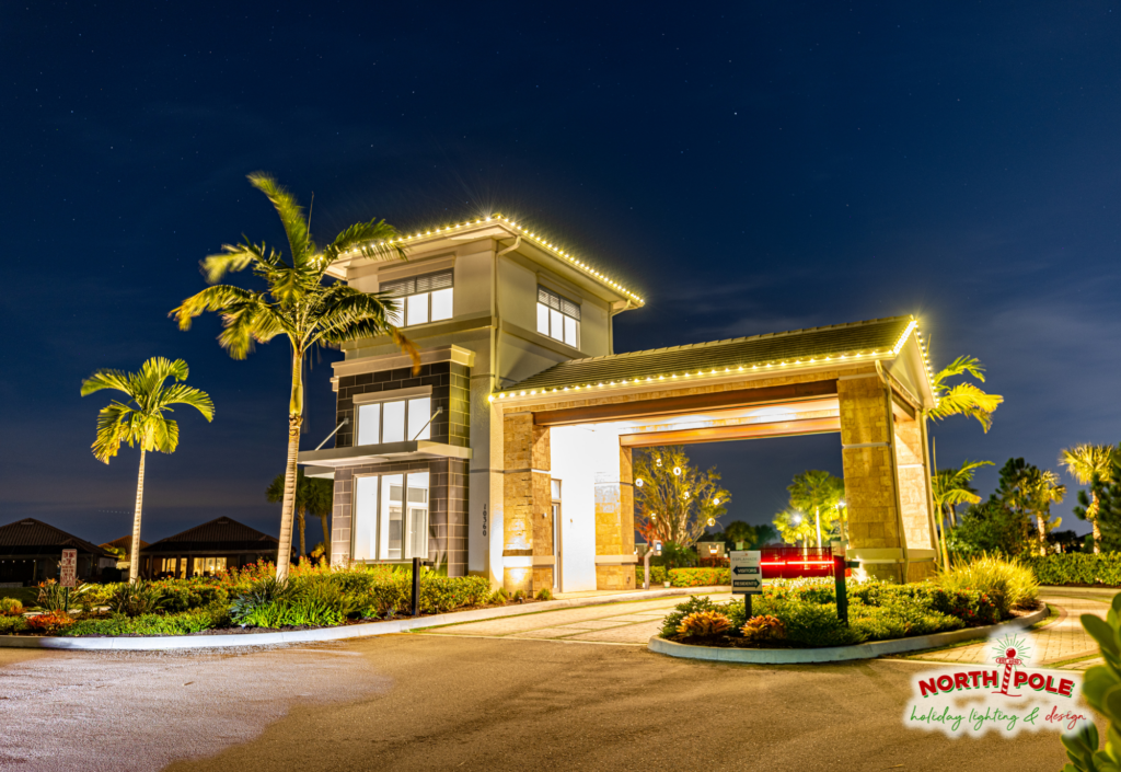 Commercial HOA entrance holiday lighting at Esplanade featuring precision warm white LED roofline outlining and lit palm trees.