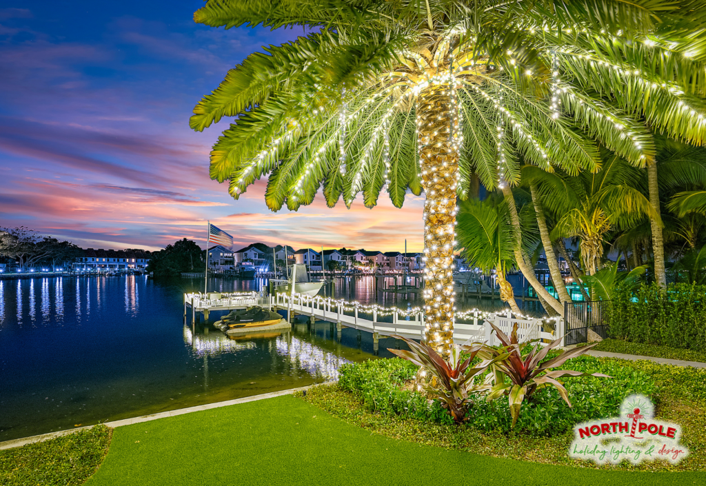 Luxury waterfront holiday lighting in Jupiter featuring a warm white LED wrapped palm tree and illuminated boat dock along the Intracoastal.
