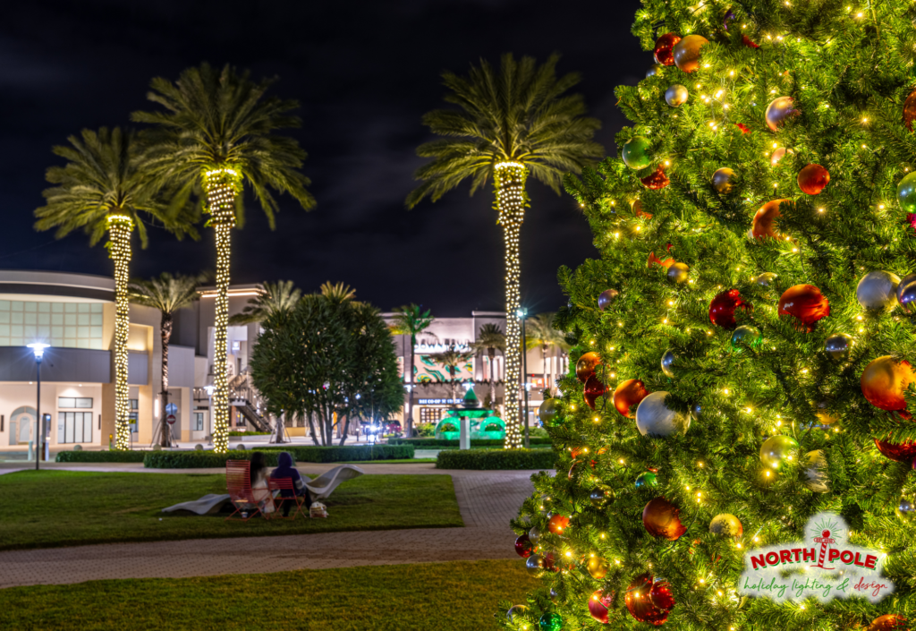 Detail shot of decorated commercial Christmas tree branch with shatterproof ornaments and warm white LED palm wraps, installed at Downtown Palm Beach Gardens.