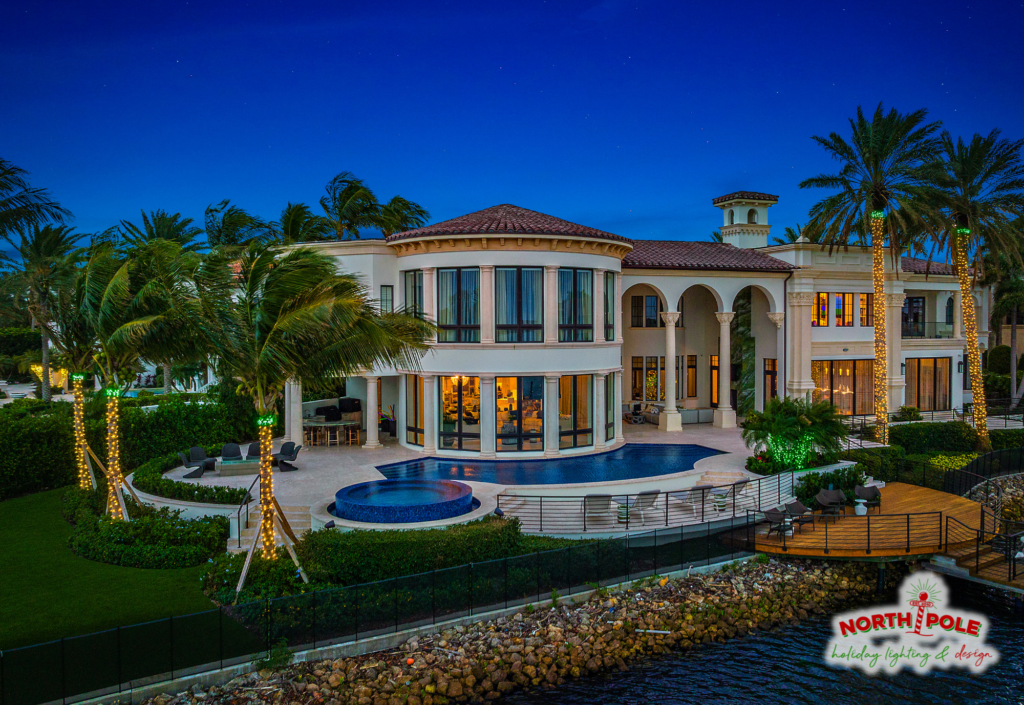 Ultra-luxury waterfront estate holiday lighting in Palm Beach featuring high-density LED palm wraps with green crowns.