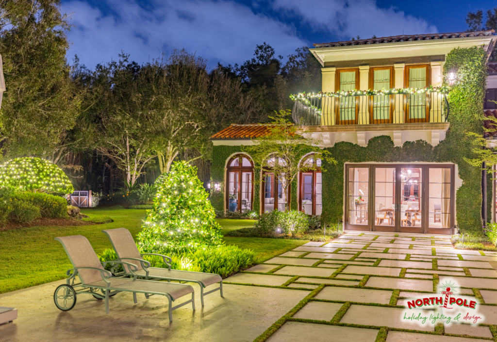 Luxury Wellington estate holiday lighting featuring illuminated manicured shrubbery, a lit balcony garland, and warm white LED landscape accents.